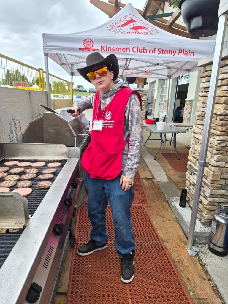 Youth standing by BBQ with sunglasses
