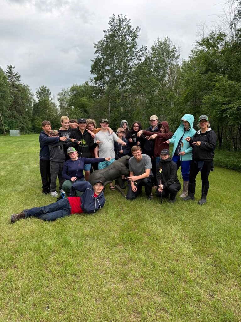 A group of young people surrounding an archery target