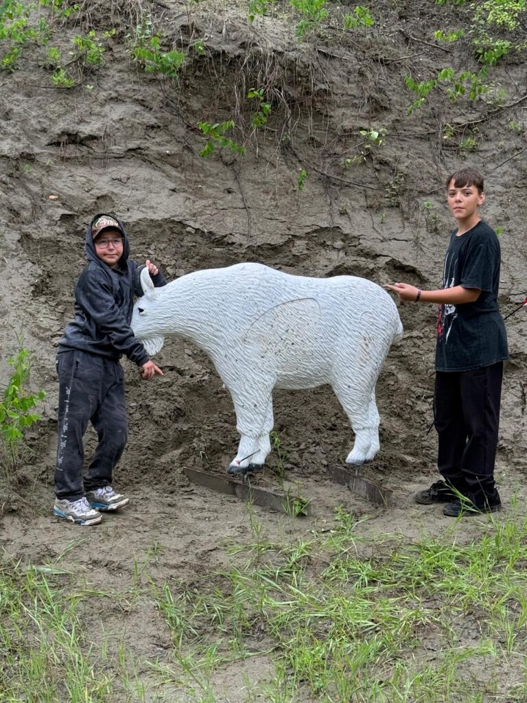 Two boys with an archery target of a mountain goat