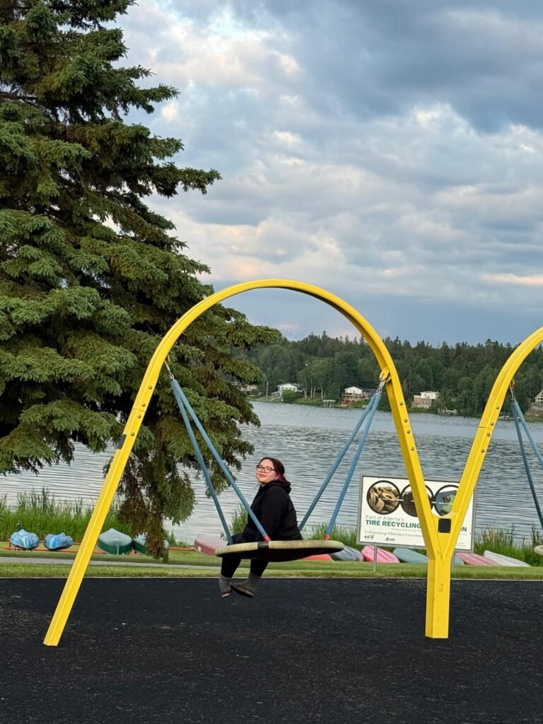 A young woman on a swing by a lake