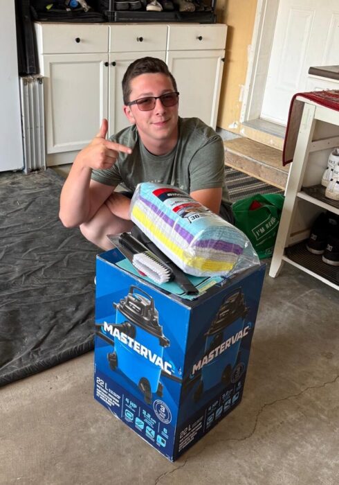 A young adult with a shop vac in a box